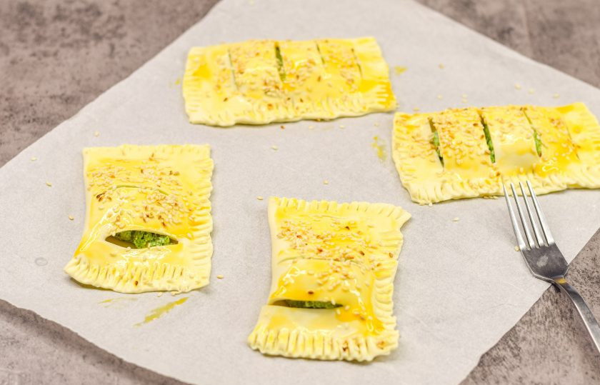 1. Этап. Слоеные пирожки с рикоттой и шпинатом: Смажьте заготовки слоек взбитым желтком и по желанию посыпьте кунжутом.