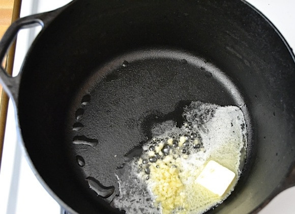 1. Этап. Перловка с шампиньонами: 1. Очистите чеснок и измельчите его ножом. Грибы вымойте и нарежьте пластинками. Казанок разогрейте и добавьте сливочное масло, затем выложите чеснок и обжаривайте несколько минут.