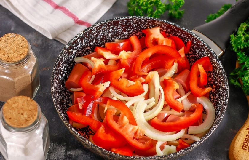 1. Этап. Сосиски по-корейски: Болгарский перец любого цвета очистите от семян и промойте. Лук и морковь очистите от кожуры и также промойте. Нарежьте болгарский перец и лук полукольцами, а морковь натрите на терке с мелкими ячейками. Добавьте к сосискам и обжарьте примерно 2-3 минуты.