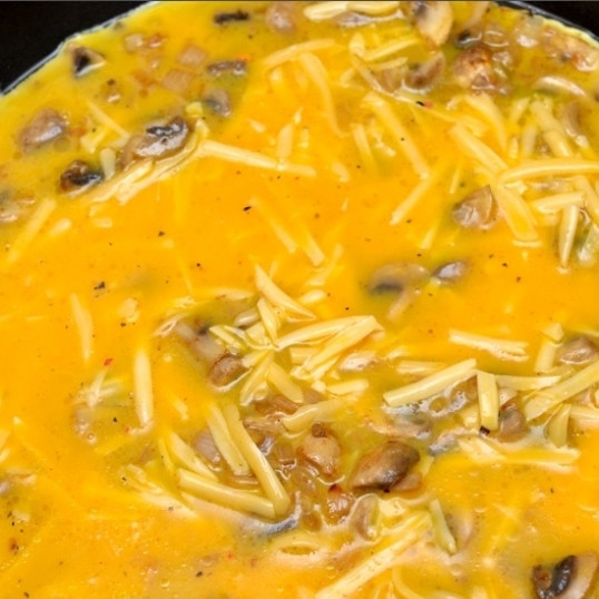 1. Этап. Яичница-болтунья с грибами: Заливаем в сковороду взбитые венчиком яйца, добавляем тертый сыр и молоко. Перемешиваем и жарим на среднем огне. Когда яйца схватятся (20-30 секунд), начинаем помешивать их лопаткой, чтобы равномерно обжарились со всех сторон.