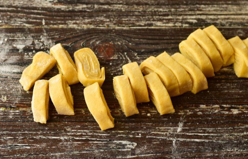 1. Этап. Гороховый суп с лапшой: Посыпьте пласт мукой, скрутите в рулет и нарежьте его на кусочки.