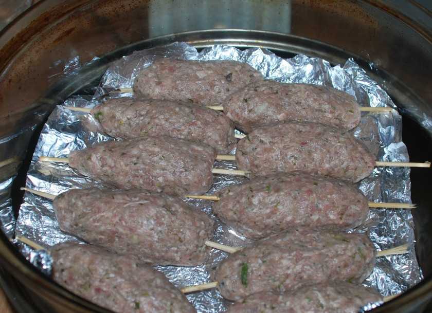 1. Этап. Люля-кебаб в аэрогриле: Фарш отбиваем и отправляем в холодильник. На дно аэрогриля наливаем жидкий дым. Ставим среднюю решетку. Включаем разогрев. И начинаем лепить кебабы на палочки. Застилаем фольгой решетку и выкладываем кебабы.