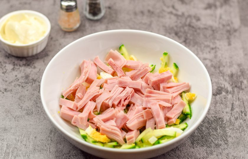 1. Этап. Салат Марианна: Переложите яйцо и огурец в салатник. Ветчину нарежьте небольшими полосками и также добавьте в салат.