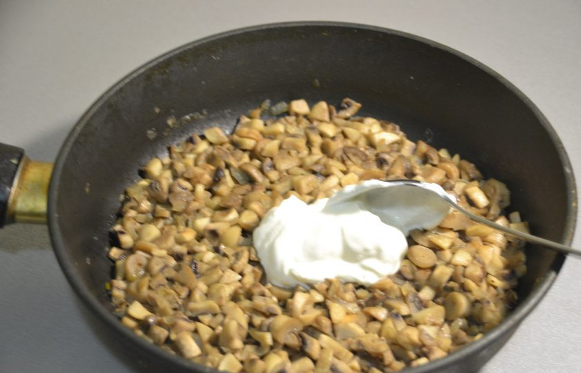 1. Этап. Перепечи с грибами: Дайте грибам остыть до комнатной температуры, после чего положите в них две столовые ложки сметаны.