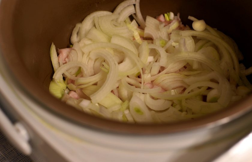 1. Этап. Паштет из куриной печени в мультиварке: Свежее свиное сало, желательно с мясными прослойками, нарежьте тонкими пластиками и уложите на дно чаши мультиварки. Сверху уложите слой лук, нарезанного довольно крупно.