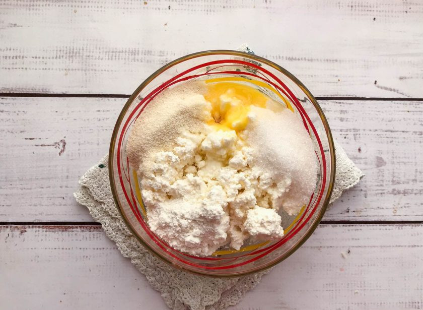 1. Этап. Сырники с малиной: В глубокой тарелке смешайте творог, яйцо, ванильный сахар и обычный сахар.