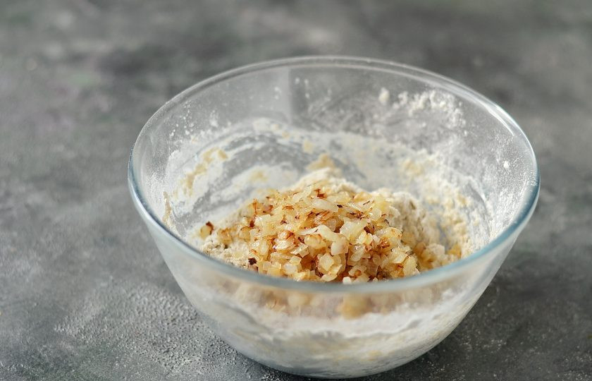 1. Этап. Луковый хлеб в духовке без дрожжей: Добавьте жареный лук в тесто, перемешайте, чтобы он равномерно распределился.