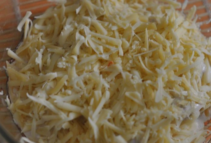 1. Этап. Пельмени в сметане: Сверху посыпаем их тертым на крупной терке сыром и ставим форму в разогретую до 180 градусов духовку.