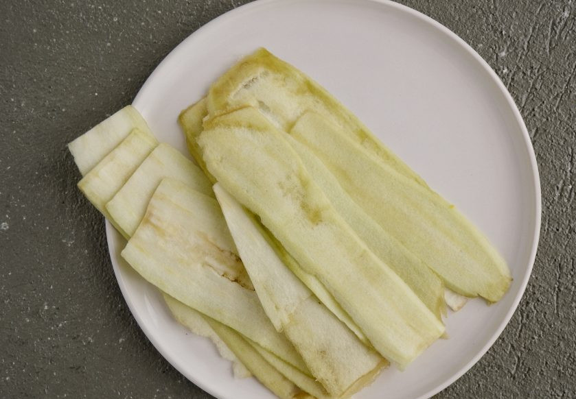 1. Этап. Бекон из баклажанов: Помойте баклажан, очистите его от кожуры. Затем нарежьте вдоль на тонкие пластины.