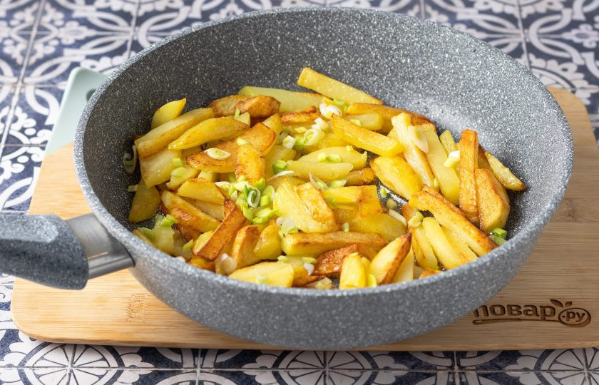 1. Этап. Жареная картошка на оливковом масле: Переверните подрумяненный картофель и добавьте белую часть лука. Жарьте вторую сторону почти до готовности. Периодически перемешивайте картофель, чтобы он не подгорал.