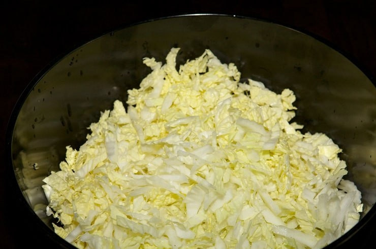 1. Этап. Салат с кукурузой и крабовыми палочками: Капусту промойте и нашинкуйте. Положите её в большую салатницу.