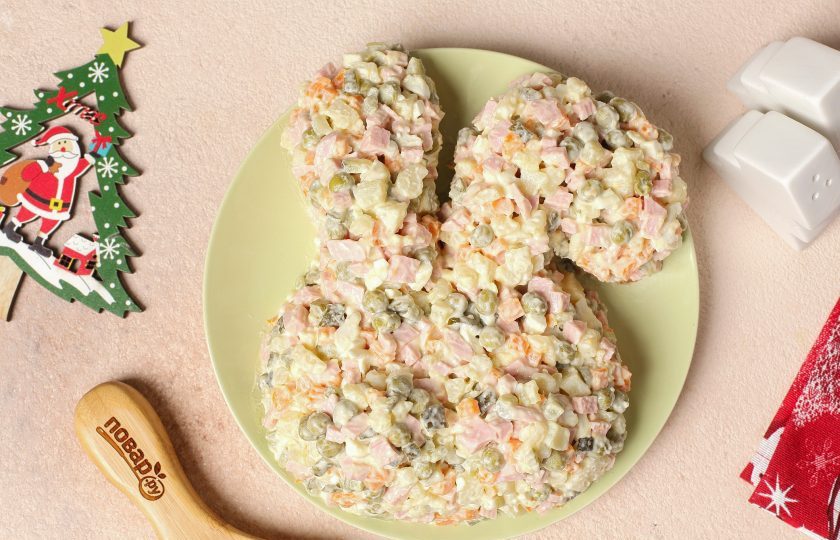 1. Этап. Салат Оливье на год Кролика: Выложите салат на плоскую тарелку, сформировав при помощи ложки мордочку в виде кролика. Украшать салат лучше незадолго до подачи на стол.