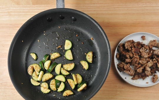 1. Этап. Запечённые фарфалле: 3. В это же время обжарьте сосиску в течение 4 минут в небольшом количестве масла, помешивая. Затем уберите фарш. На той же сковороде обжарьте цуккини с чесноком в течение 5 минут, пару раз перевернув.