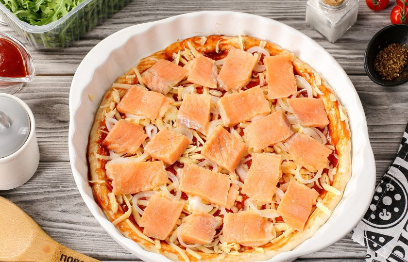 1. Этап. Пицца с рыбой: Сверху выложите нарезанную тонкими кусочками красную рыбу. Если у вас свежая рыба, то можно слегка её посыпать сверху солью.