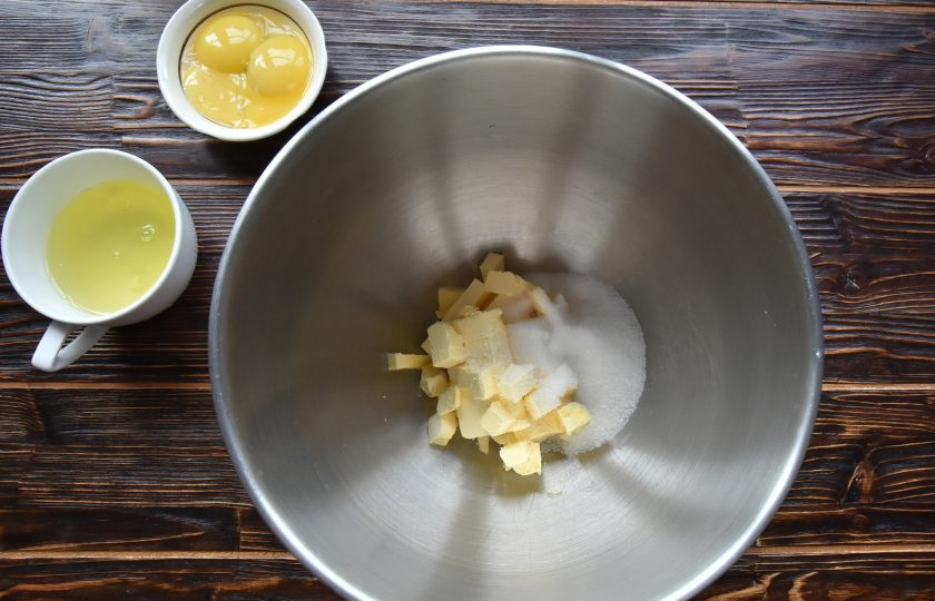 1. Этап. Пирог Ложный сырник: Масло натрите на терке или нарежьте мелким кубиком. Всыпьте 50 граммов сахара, соль, ванильный сахар.