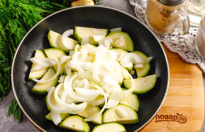 1. Этап. Теплый салат с куриными сердечками: Кабачок нарежьте крупными кусочками, лук — полукольцами. Обжарьте в 1 ст.л. растительного масла примерно 5-6 минут, следя за тем, чтобы лук не пригорел.