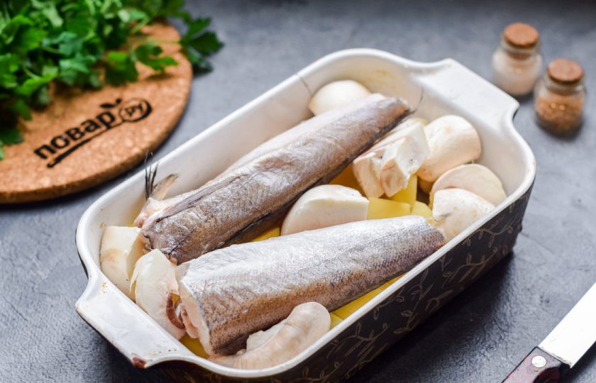 1. Этап. Рыба запеченная с грибами и картофелем: Выложите картофель и грибы в форму, добавьте тушки хека.