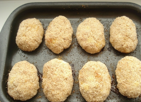 1. Этап. Котлеты из куриной грудки в духовке: Формируем из массы овальной формы котлеты. Обваливаем каждую в панировочных сухарях. Выкладываем куриные котлетки на смазанный сливочным маслом противень. Ставим в духовку на 40 минут. Температуру выставляем 180 градусов.