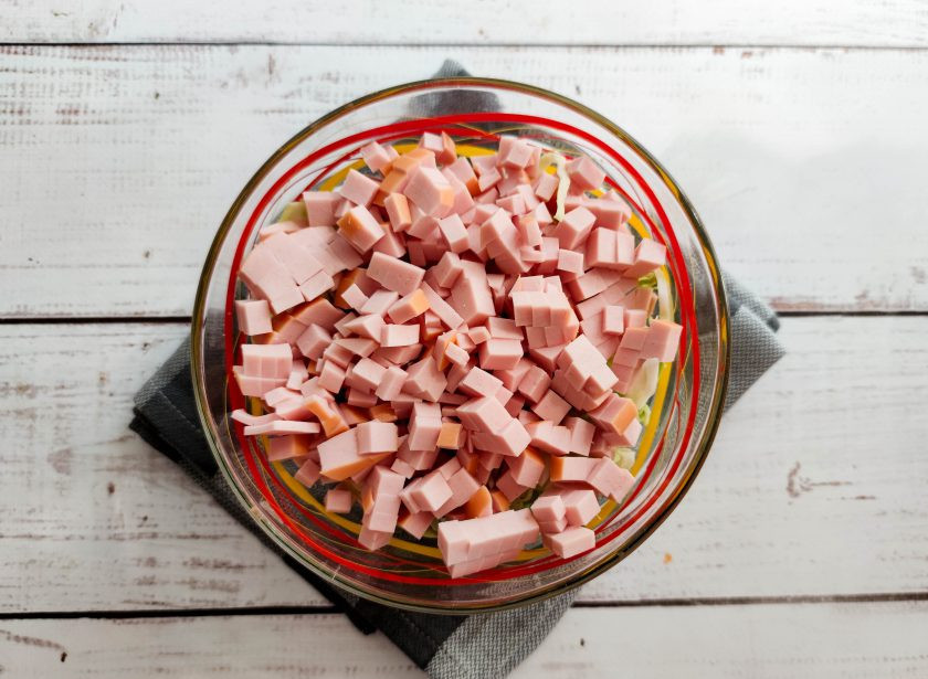 1. Этап. Салат из капусты, горошка и колбасы: Колбасу нарежьте небольшими кубиками и добавьте к капусте.