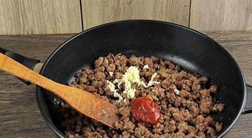 1. Этап. Запеканка с фаршем: Далее к фаршу добавьте соль, перец, томатную пасту, измельчённый чеснок и воду. Тушите ингредиенты под крышкой на медленном огне 25 минут.