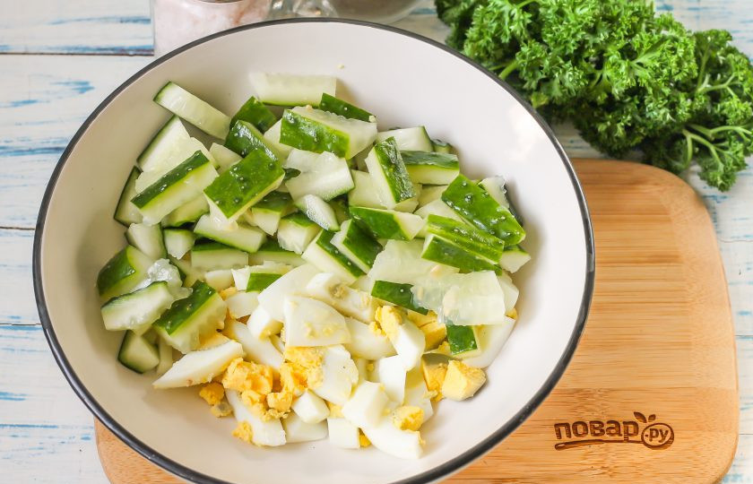 1. Этап. Салат из свиного языка с огурцом: Куриные яйца отварите заранее и остудите. Очистите от скорлупы и промойте в воде вместе с огурцом. У овоща срежьте хвостики. Нарежьте огурец - брусочками, а куриные яйца - кубиками и высыпьте обе нарезки в глубокую емкость.