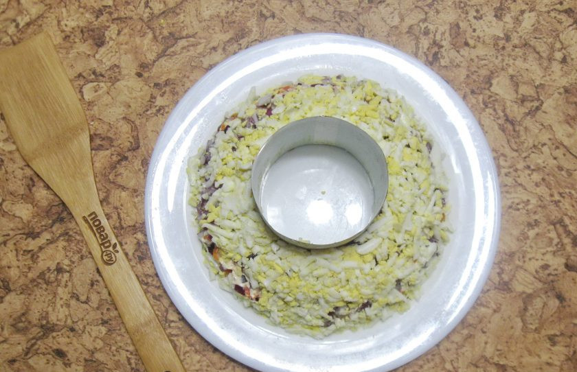 1. Этап. Салат Гранатовый браслет с языком: Яйца сварите вкрутую и натрите на терке. Выложите на слой лука, посолите, поперчите и смажьте майонезом.