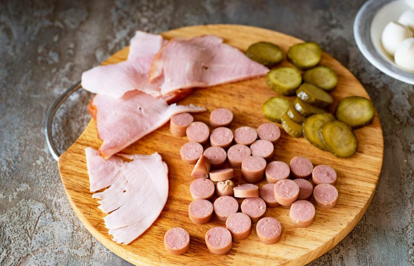 1. Этап. Пицца Виктория: За это время нарежьте колбаски тонкими кружочками, также тонкими кружочками нарежьте маринованный огурчик и тонкими ломтиками ветчину.