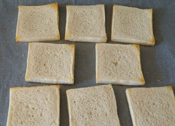 1. Этап. Гренки с сыром: 3. С хлеба срежьте корочки. Выложите хлеб на покрытый бумагой для выпечки противень. Отправьте в духовку на пару минут, чтобы хлеб подсох. По истечению минутки - переверните хлеб на другую сторону.