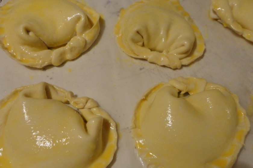 1. Этап. Пирожки с адыгейским сыром: 2. Начинку выкладываем по центру квадратиков теста. Квадратики складываем по диагонали, скрепляем кончики. Два оставшихся кончика как бы огибают получившийся треугольничек и тоже скрепляются. Получается своего рода форма пельмешек. Теперь берем желток, добавляем к нему немного воды (1 ст. ложку) и все хорошенько взбиваем. Смазываем полученной смесью будущие пирожки.