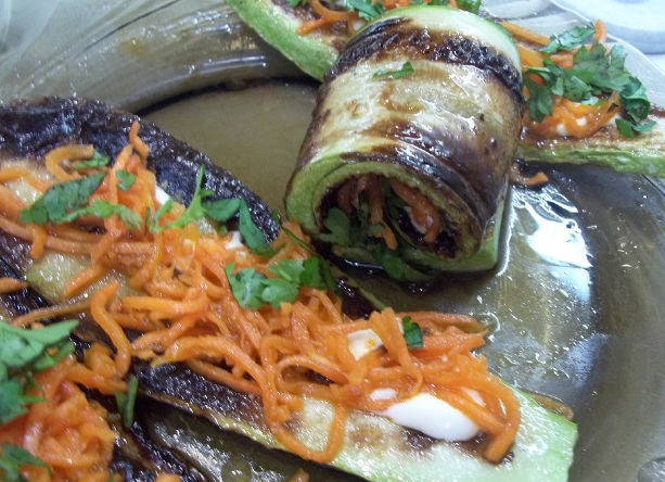 1. Этап. Закусочные рулетики из кабачков: Вымойте и обсушите кинзу. Измельчите листики, присыпьте ими кабачки. Сверните их рулетиком и выложите на блюдо для подачи 