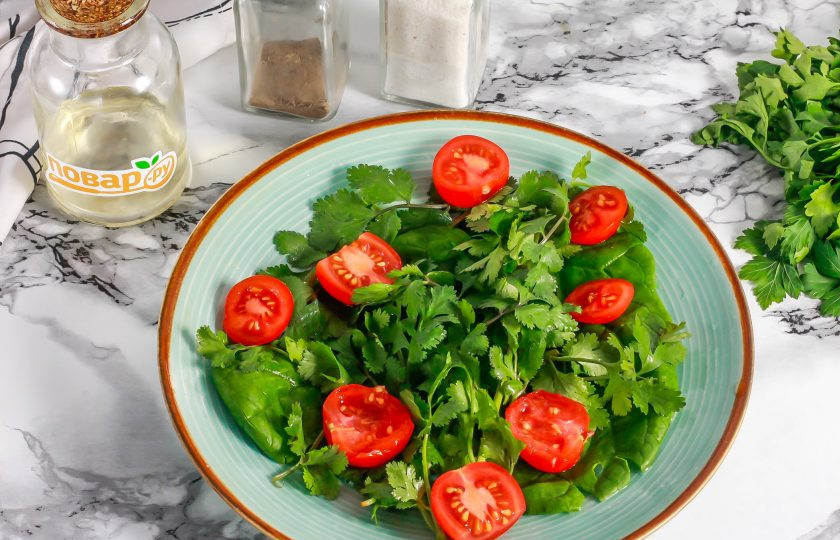 1. Этап. Салат с куриной печенью и кинзой: Промойте и разрежьте пополам помидоры черри, выложите их на тарелку.