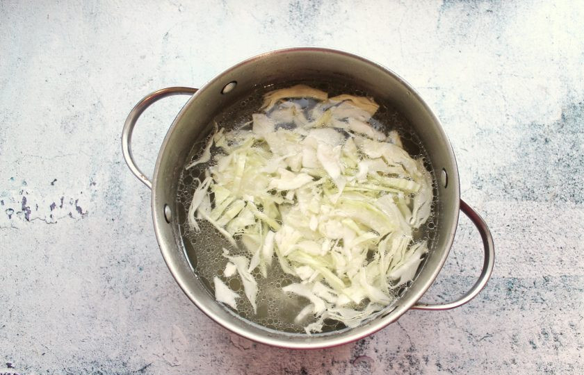1. Этап. Борщ на квасе: Готовое мясо достаньте, бульон процедите и перелейте в чистую кастрюлю. Капусту порежьте тонкой соломкой и добавьте в кипящий бульон. Варите все в течение 10 минут.
