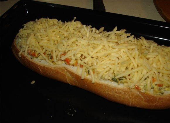 1. Этап. Фаршированный батон в духовке: 5. Натрите на терке сыр, присыпьте им сверху. Отправьте в разогретую до 180 градусов духовку и выпекайте минут 20-30 до аппетитной корочки.