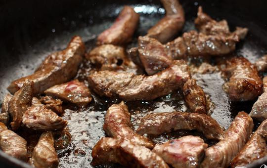 1. Этап. Тушеное мясо: 2. Кусочки мяса необходимо обжарить со всех сторон. Мясо обжариваем до появления румяной корочки. Затем перекладываем мясо в другую кастрюлю. Нарезаем четверть-кольцами лук, обжариваем на сковороде в протяжении одной-двух минут, добавив чайную ложку кукурузной муки.