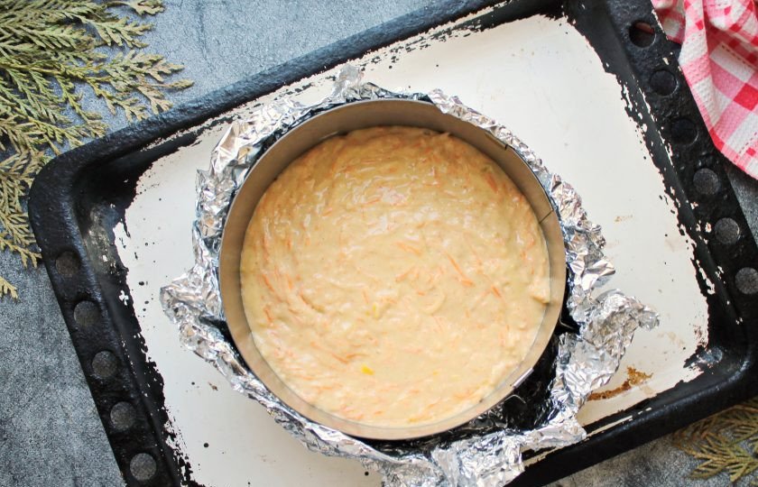 1. Этап. Морковный торт с карамелью: Поставьте кулинарное кольцо диаметром 16-18 сантиметров на фольгу и закрепите, сделав дно. Установите кольцо с фольгой на противень и переложите в него тесто, разровняйте.