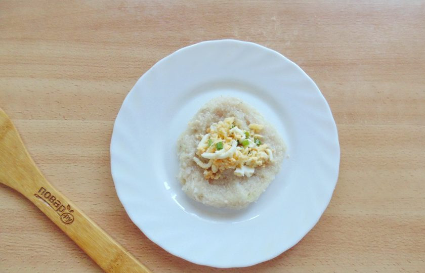 1. Этап. Зразы из судака: Порцию рыбного фарша в виде лепешки выложите на тарелку. На середину добавьте начинку из яйца, зеленого лука и сыра.