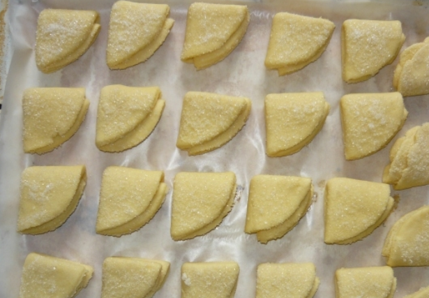 1. Этап. Конвертики из творожного теста: Обмакиваем кружочки в сахар (с одной стороны) и сворачиваем пополам (сахарной стороной внутрь). Вновь обмакиваем тесто в сахар, затем еще раз сворачиваем сахарной стороной внутрь. Застилаем противень бумагой для выпечки и раскладываем на нем печенье, посыпаем сверху сахаром. Выпекаем в духовке до золотистого цвета при температуре 250 градусов.