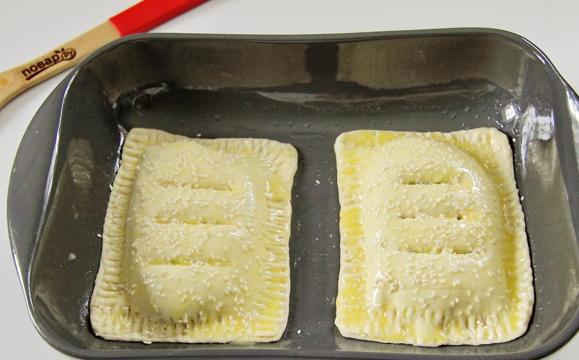 1. Этап. Рыба, запеченная в тесте в духовке: Перенесите рыбу в форму для запекания, смазанную предварительно маслом. Сделайте сверху несколько надрезов ножом для выхода пара, смажьте желтком и посыпьте по желанию верх кунжутом. Выпекайте при 180 градусах до готовности или появления румяной корочки.