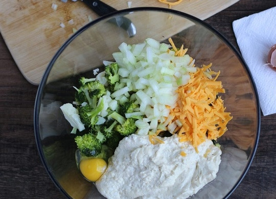 1. Этап. Запеканка из брокколи: 4. В глубокой мисочке соедините брокколи, измельченный кубиками лук, тертый сыр (часть отложите), яйцо и сырный соус. Посолите и поперчите по вкусу, аккуратно все перемешайте.