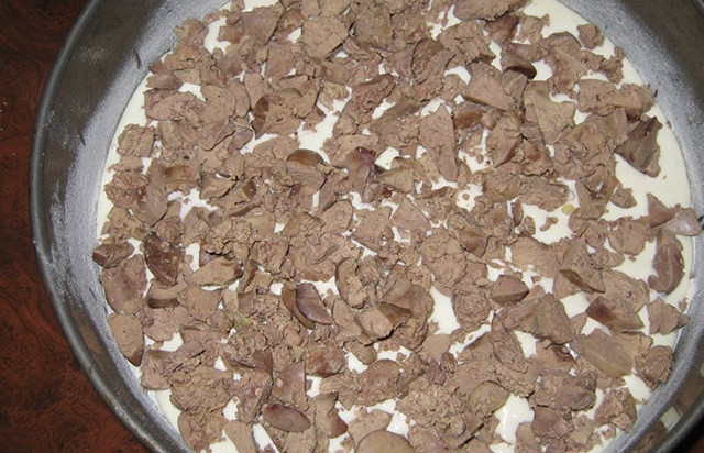 1. Этап. Пирог из куриной печени: На дно формы для выпечки влейте немного масла и посыпьте муку. Влейте половину теста. Выложите печень кусочками. Посолите её и поперчите.
