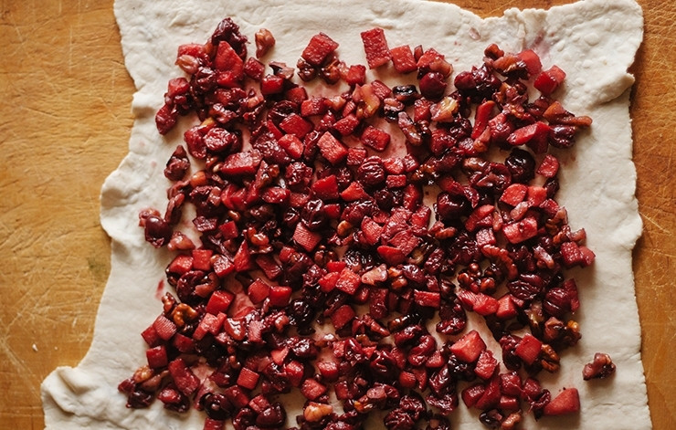 1. Этап. Вишневый штрудель из готового теста: Оставьте начинку остывать, а пока приступите к раскатыванию теста. Сделайте из него квадрат. Потом выложите приготовленные фрукты с ягодами равномерно на всю поверхность.