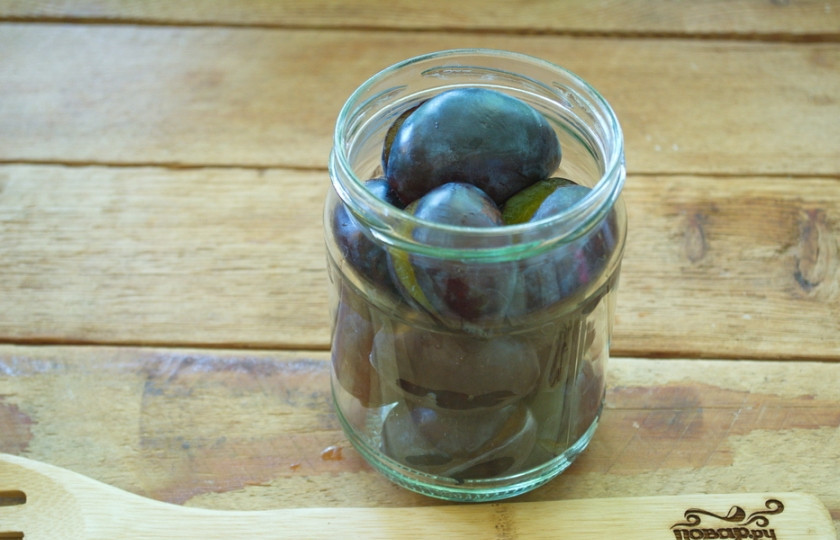 1. Этап. Закатка слив на зиму: В каждую стерильную баночку добавьте по паре бутончиков гвоздики, пару горошин душистого перца, затем заполните баночки сливами.