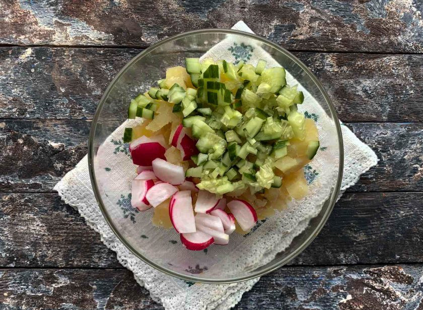 1. Этап. Окрошка с крабовыми палочками: Огурец и редиску хорошо помойте под проточной водой, обсушите бумажным полотенцем, нарежьте небольшими кусочками и добавьте в тарелку.