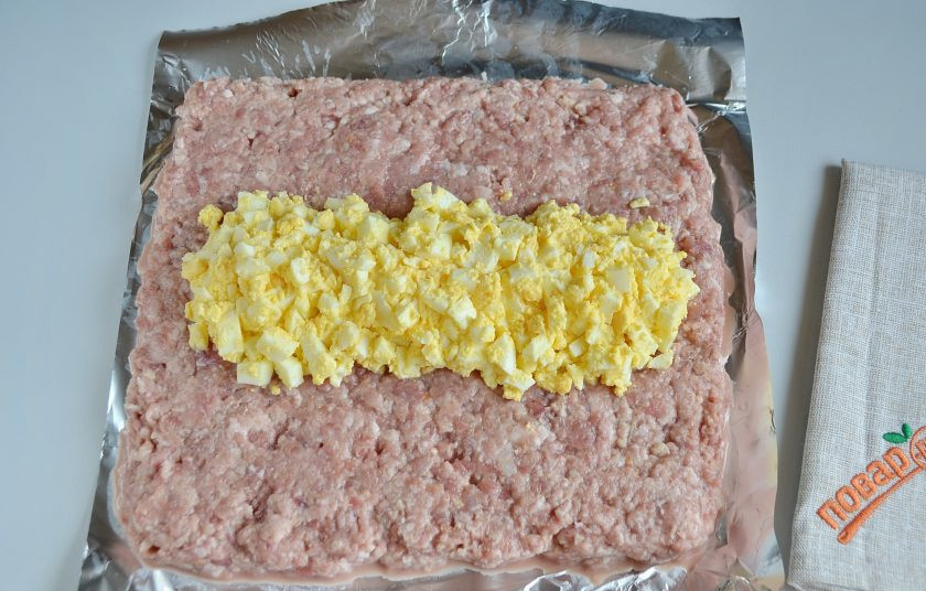 1. Этап. Мясной рулет с яйцом, как в садике: 7. На рабочем столе расстелите пищевую пленку или фольгу. Распределите фарш толстым слоем, примерно 2-2,5 см. По центру положите яичную начинку.