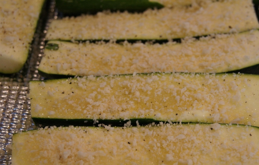 1. Этап. Кабачки, запеченные в духовке с сыром: 1. Тщательно помоем и обсушим кабачки. Разрезаем каждый вдоль на две-четыре части (в зависимости от размера). Смазываем маслом, натираем солью. Посыпаем половиной измельченного сыра.