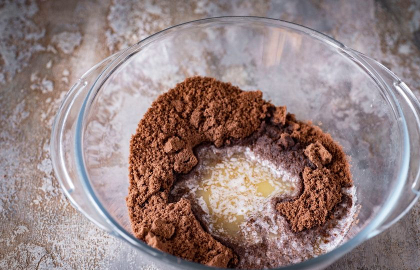 1. Этап. Шоколадный чизкейк с выпечкой: Выложите крошку из блендера в просторную миску и добавьте растопленное предварительно в сотейнике на маленьком огне сливочное масло.