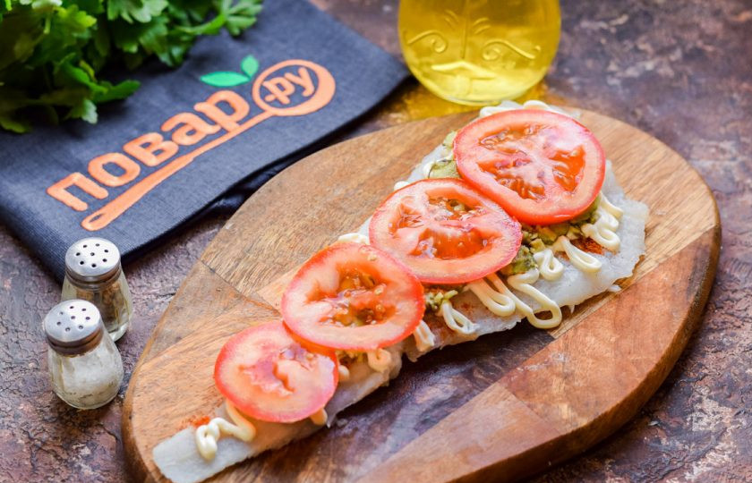 1. Этап. Рыба запеченная с авокадо: Помидор нарежьте небольшими тонкими пластинами и выложите поверх авокадо.