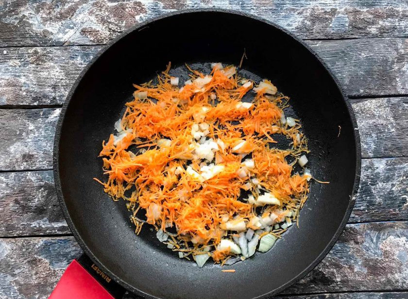 1. Этап. Сырный суп с зеленым горошком: Морковь хорошо помойте под проточной водой, очистите и натрите на средней или мелкой терке. Луковицу очистите от шелухи и мелко нарежьте. На хорошо разогретую сковороду с растительным маслом выложите овощи и обжарьте их в течение 8-10 минут, постоянно помешивая.