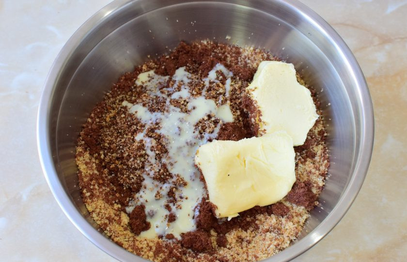 1. Этап. Пирожное Картошка в шоколадной глазури: Добавьте к бисквитной крошке сгущенку и сливочное масло. Все ингредиенты смешайте.