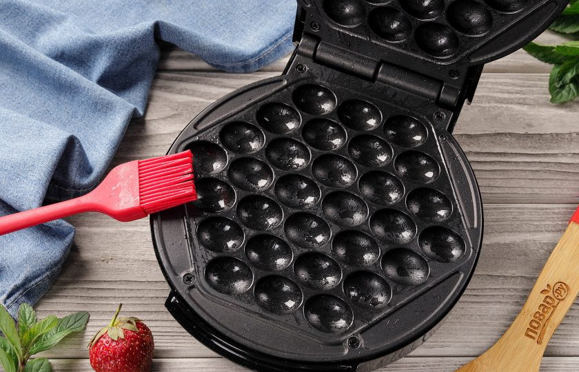 1. Этап. Гонконгские вафли: Чтобы получить вафли, которые выглядят как в Гонконге, нужно иметь в арсенале кухонной утвари специальную вафельницу. От других она отличается формой, благодаря которой вафли получаются с выпуклыми шариками. Включите вафельницу и дождитесь пока загорится красный индикатор готовности к работе. Смажьте поверхность маслом, чтобы предотвратить прилипание.